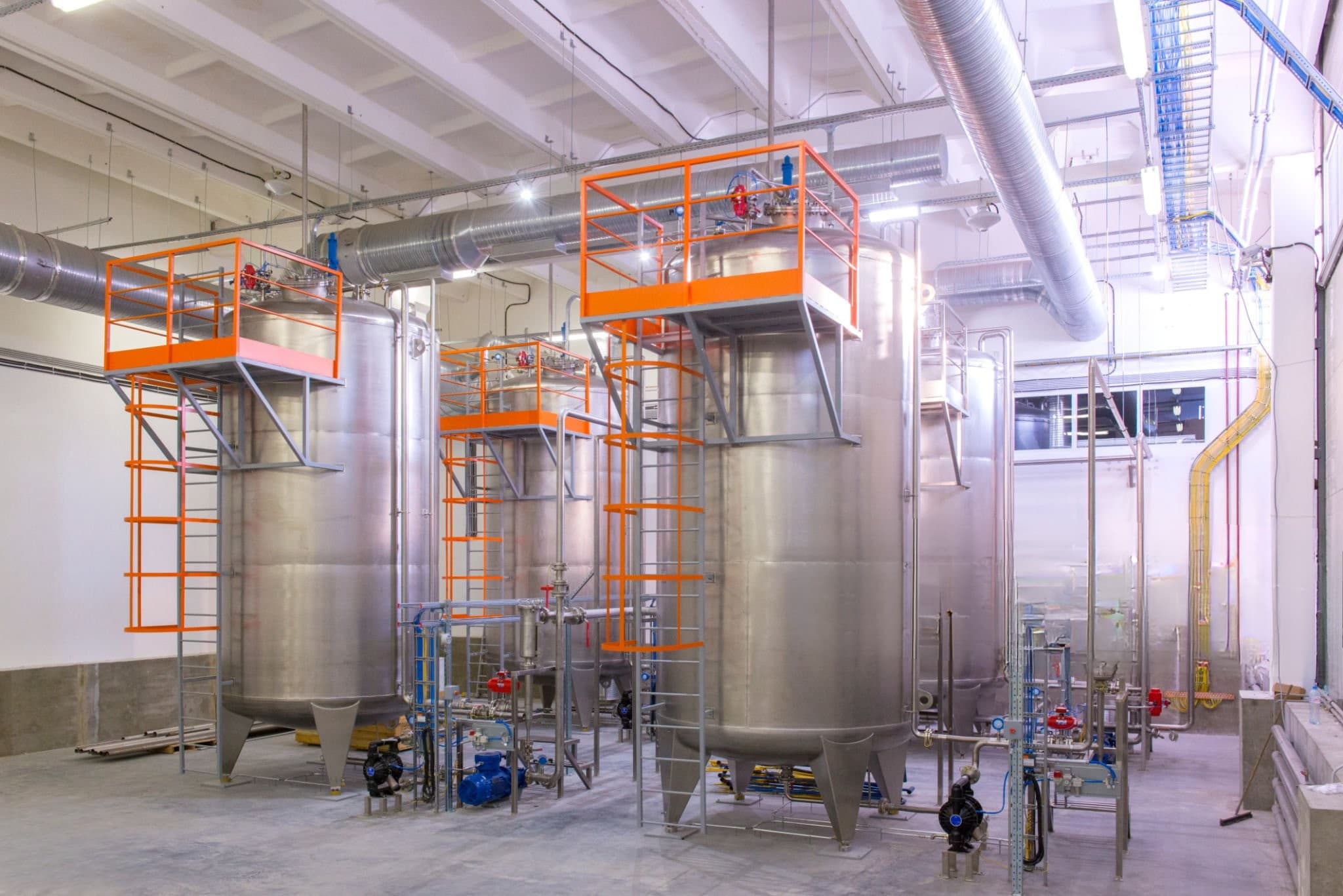 Vertical stainless steel storage tanks with top platforms and ladders